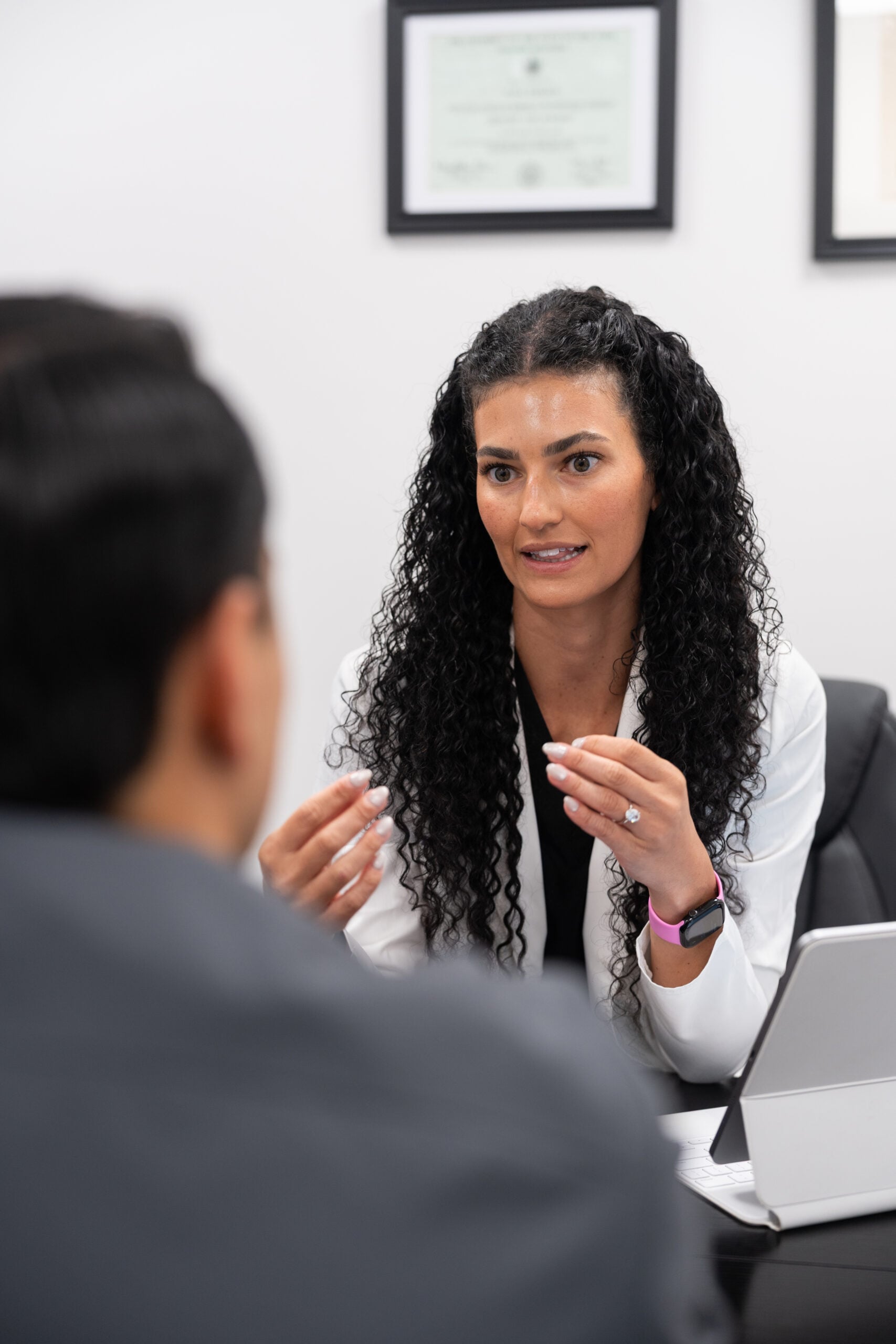 Pain Doctors Medical practitioner consulting with a patient in office, medical credentials visible on wall
