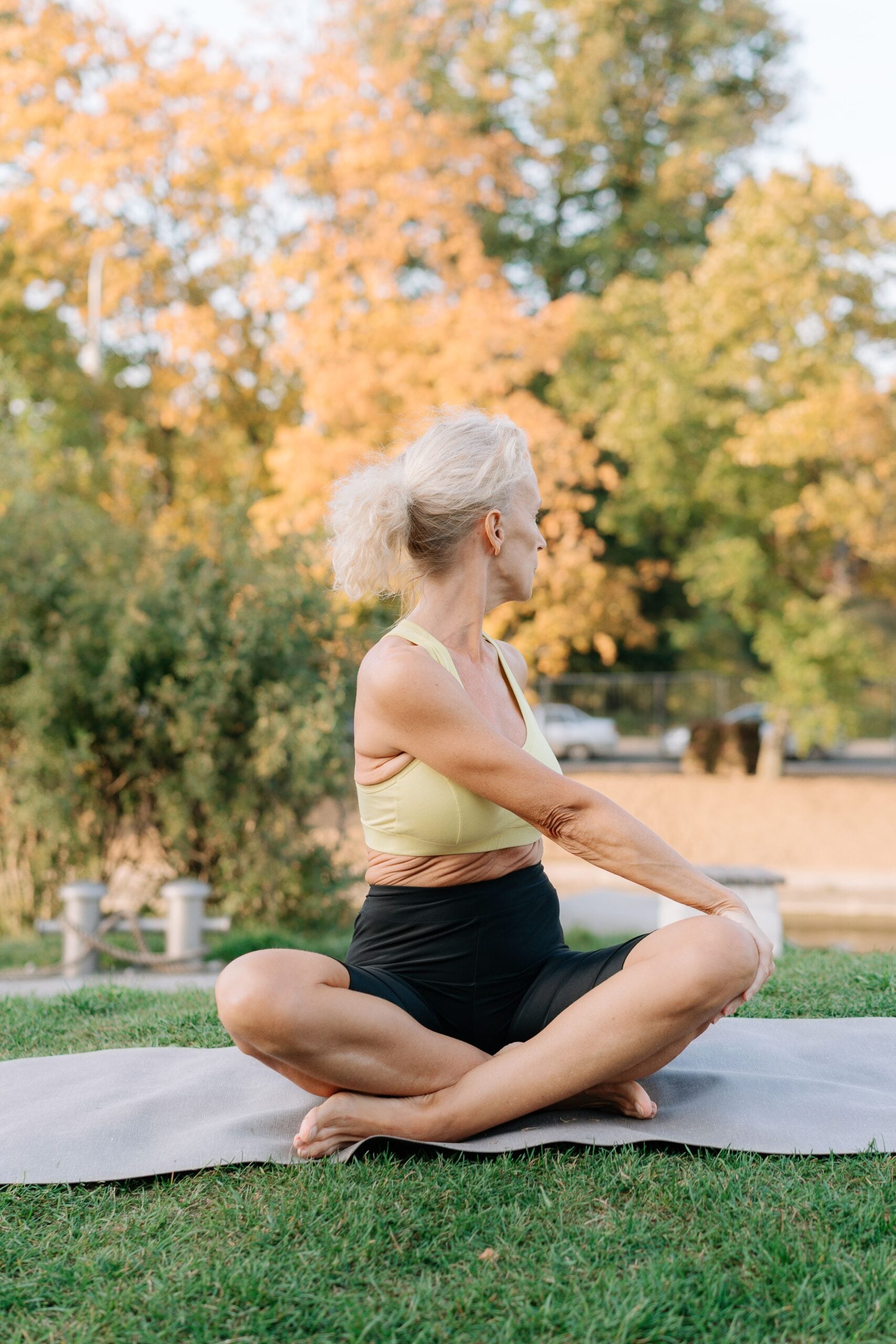 Active older woman in a seated yoga stretch outdoors, staying mobile after regenerative medicine care at Pain Doctors Medical Brooklyn