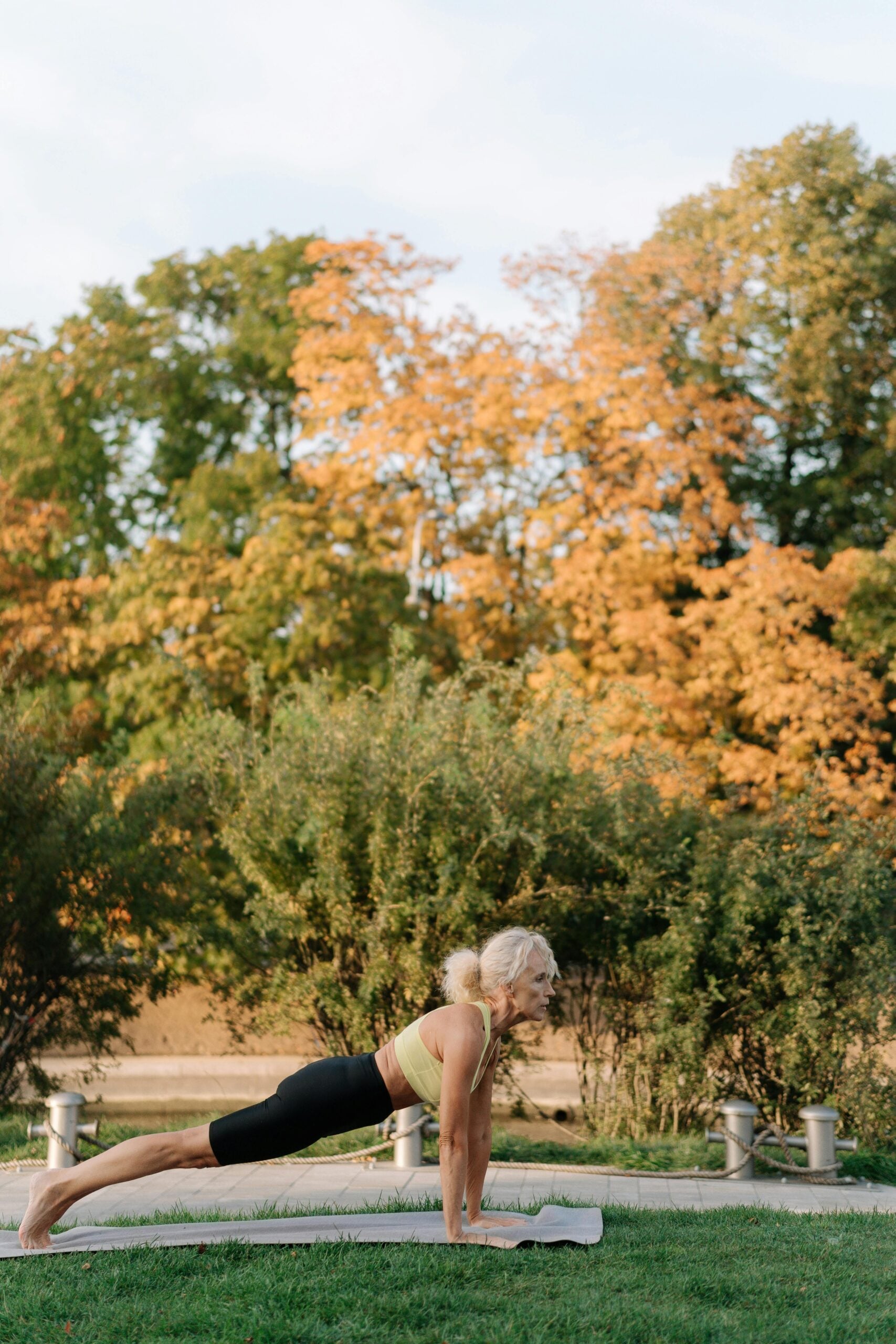 Older woman doing outdoor plank exercise after pain treatment