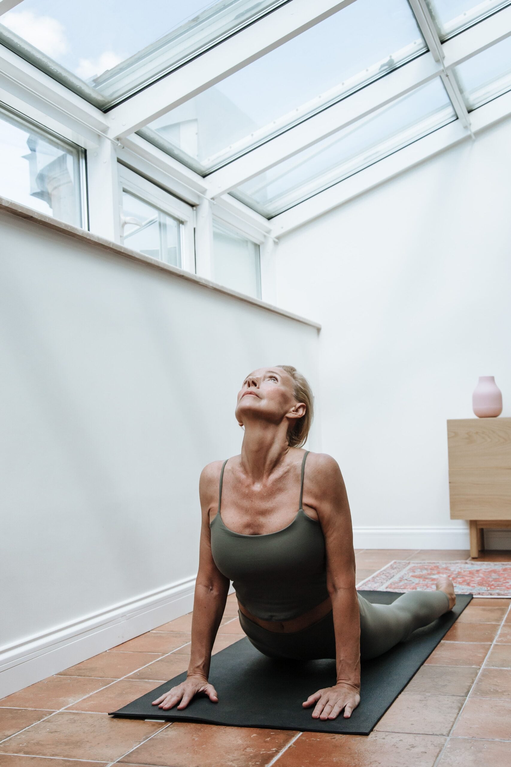 Woman doing a cobra yoga stretch on a mat under a skylight, moving freely after stem cell injection treatment