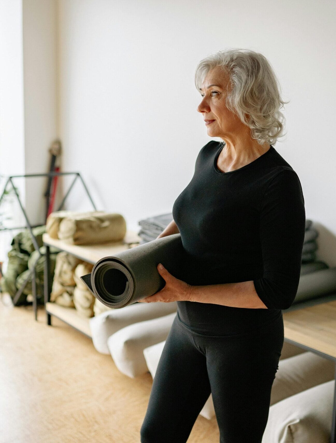 Woman carrying a yoga mat in a bright studio, moving comfortably after regenerative medicine treatment at Pain Doctors Medical