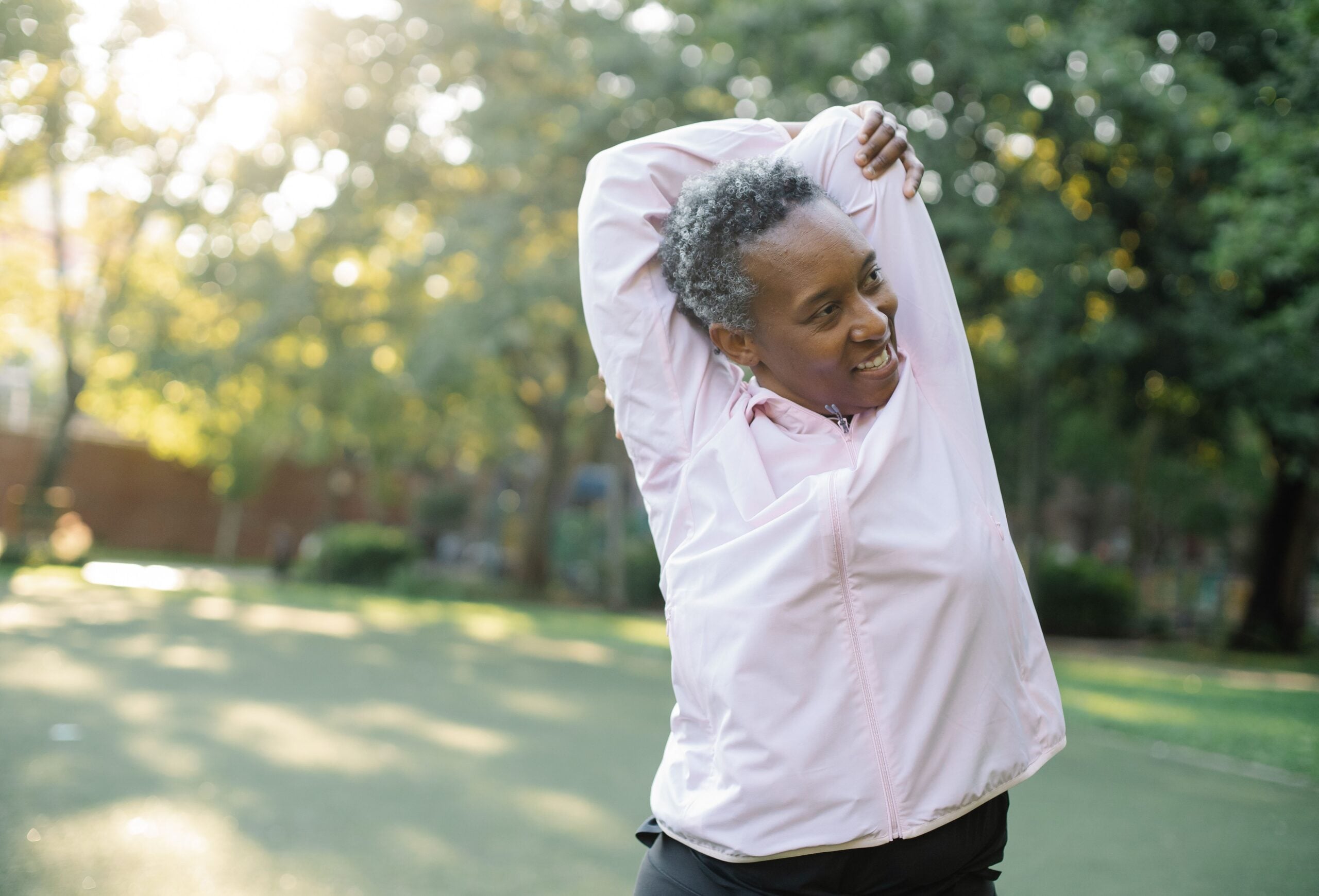 Active older woman stretching outdoors in a park, staying mobile after regenerative medicine care at Pain Doctors Medical Perth Amboy